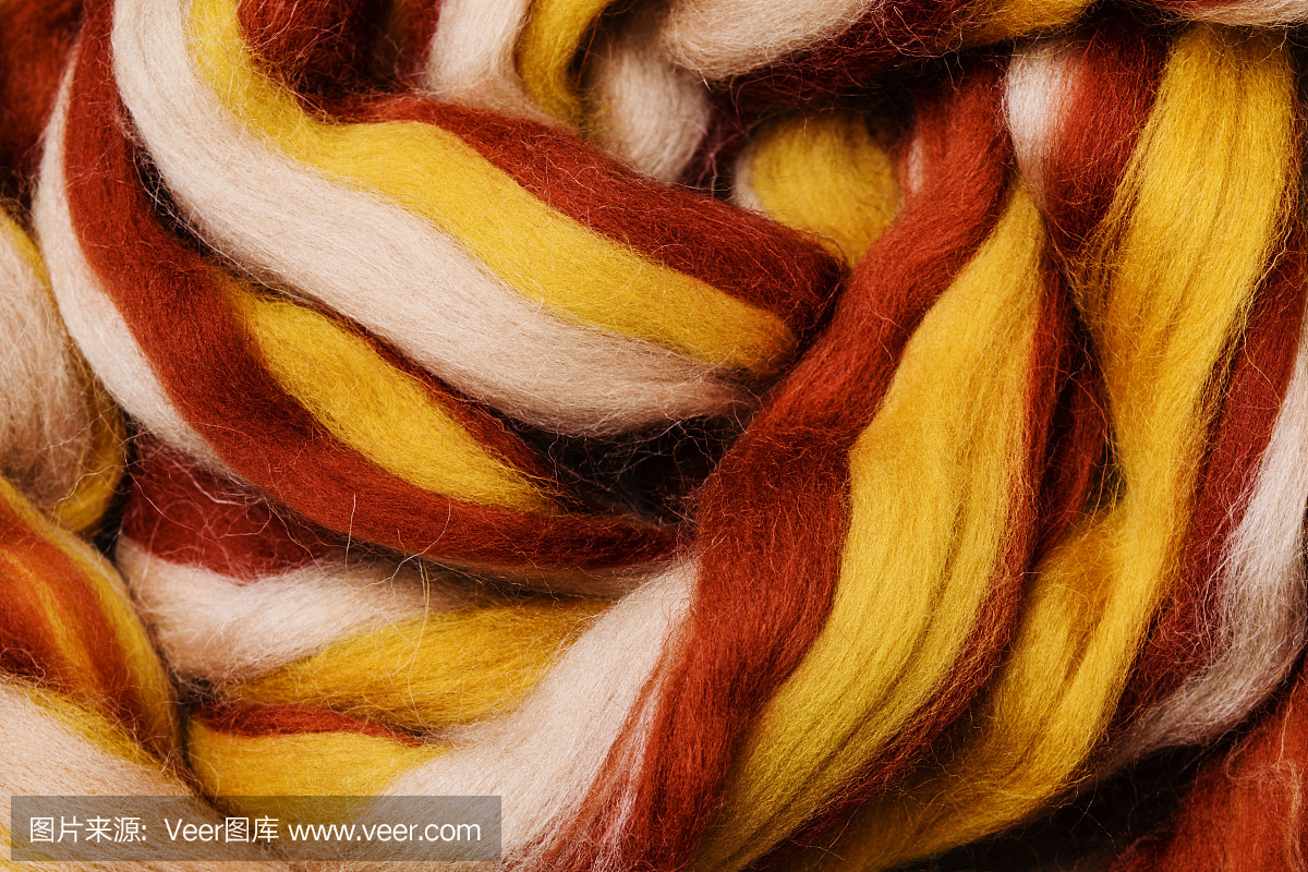 色彩鲜艳的美利奴羊毛,用于编织和缝纫,爱好。用白、黄、铜色的条纹纱折成抽象图案